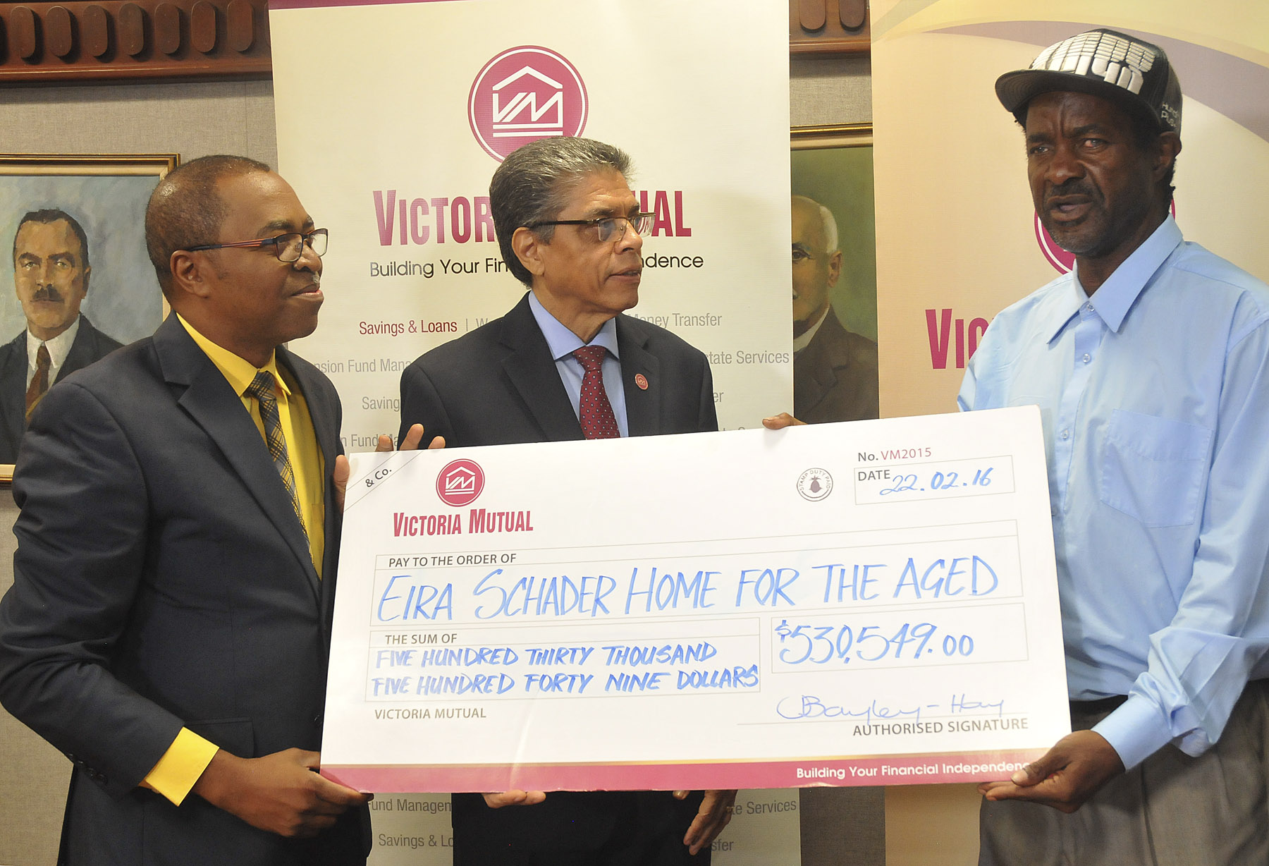 (L-R) Rev. Dr. Stevenson Samuels, Chairman, National Leadership Prayer Breakfast Committee and Richard Powell, President and CEO of Victoria Mutual Group, present Lloyd Ferguson (3rd left), manager of the Eira Schader Home For The Aged in Trench Town, with a cheque valued at over five hundred thousand dollars,