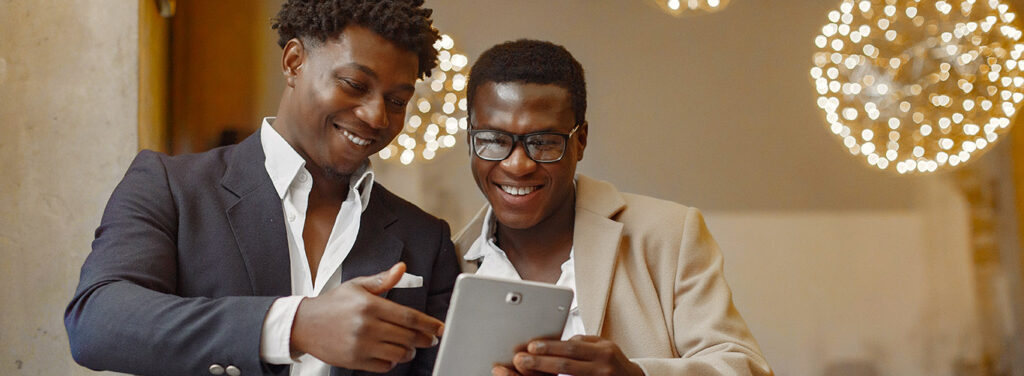 Black men in a cafe. Guy talking. Man in a black suit. Friends use the tablet.